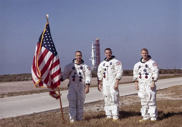 Nesta foto, os astronautas da Apollo 9, da esquerda para a direita, James A. McDivitt, David R. Scott e Russell L. Schweickart, posam em frente ao veículo espacial Apollo/Saturn V
