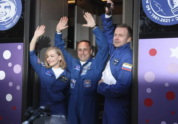 Júlia Peresild, o diretor de cinema Klim Shipenko e o cosmonauta Anton Shkaplerov acenam de um ônibus antes do lançamento no Cosmódromo de Baikonur.