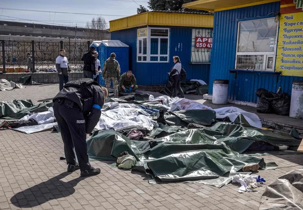 Policiai ucraniano observa os corpos de vítimas do ataque na estação de trem