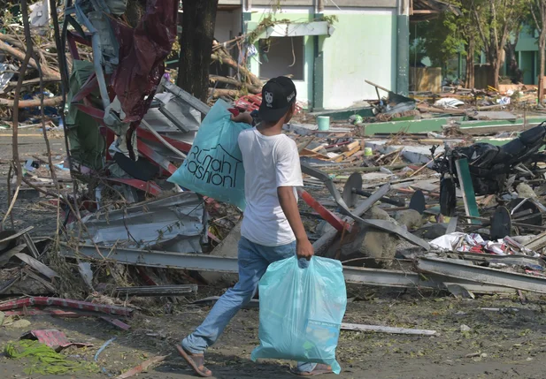 Homem caminha com sacolas após terremoto e tsunami na Indonésia