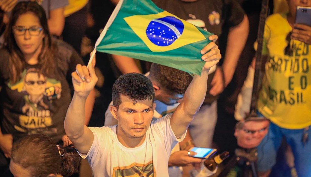 Eleitor segura a bandeira do Brasil em comemoração a vitória de Bolsonaro