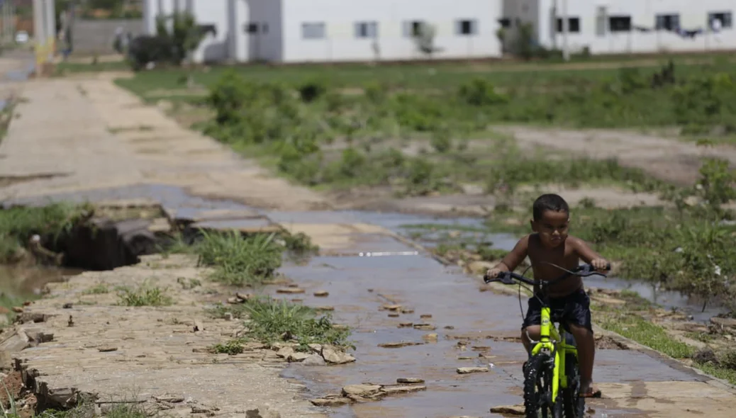 Criança andado de bicicleta em meio a água que escorre