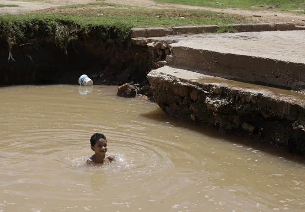 Criança tomando banho na água que se acumulou